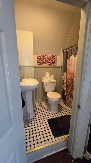 Un baño con inodoro, lavamanos y cortina de ducha.