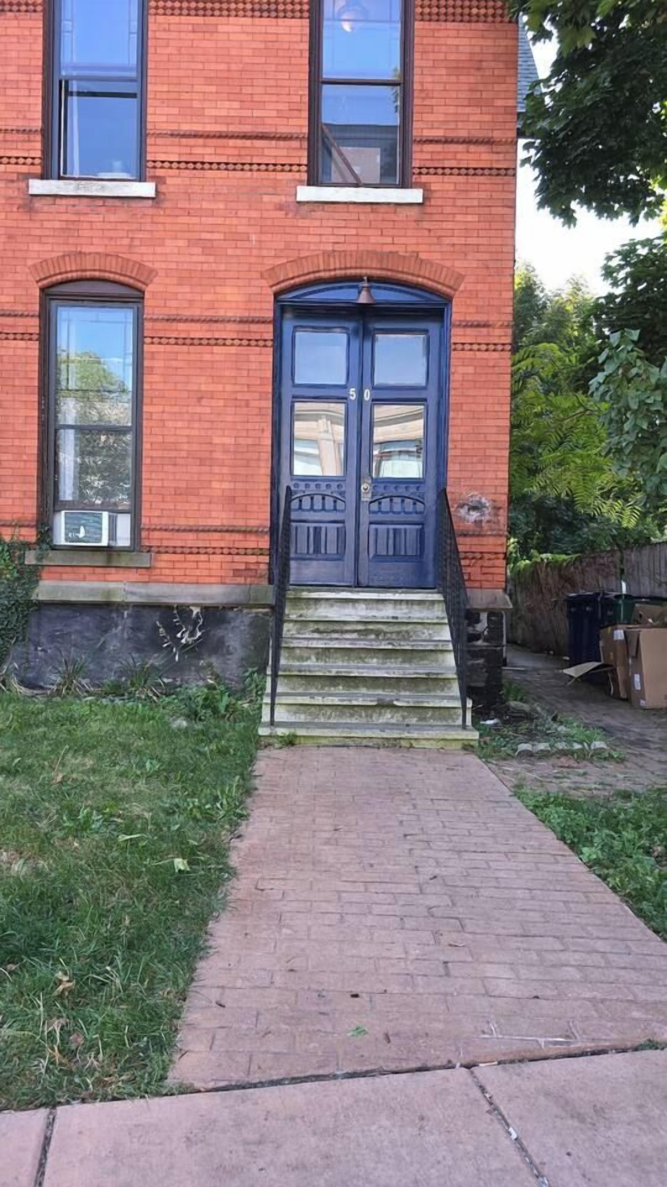A red brick building with a double door and a small set of steps leading to the entrance.