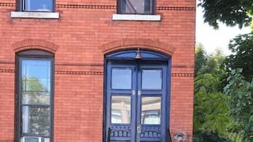 A red brick building with a double door and a small set of steps leading to the entrance.