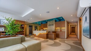 A modern hotel lobby with a reception desk, a seating area, and a kitchen visible in the background. - Charming Studio Just a Few Steps From the Beach Q6 (Rio de Janeiro)