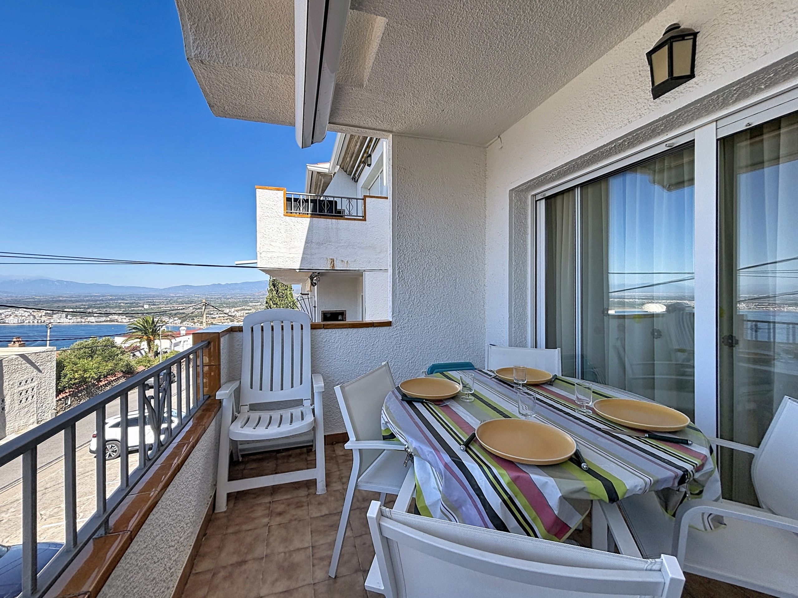 A balcony with a dining table, chairs, and a view of the city and water.