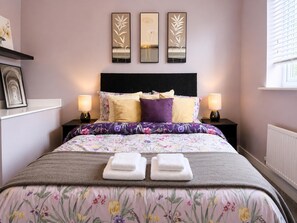 A neatly made bed with floral bedding, two bedside lamps, and a headboard with three wall-mounted mirrors. - Arnold 3-bed House, Sleeps 5 With Garden & Parking (Nottingham)