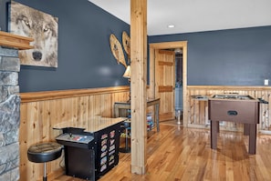 A room with a wooden bar area, a foosball table, and a stone wall. - Ski-Out to Hatley Pointe | Hot Tub | Sleeps 8 (Mars Hill)