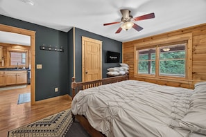A bedroom with a bed, a ceiling fan, a television, and a window with a view of greenery. - Ski-Out to Hatley Pointe | Hot Tub | Sleeps 8 (Mars Hill)