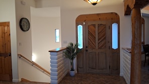 A staircase with a wooden handrail, a potted plant, and a door with a herringbone pattern.