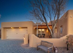 A residential property with a garage, outdoor seating area, and a tree.