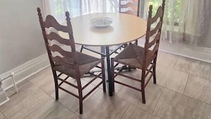 A dining area with a round table and four chairs, a rug on the floor, and curtains on the windows. - Sunlit One Bedroom In Allentown (Buffalo)
