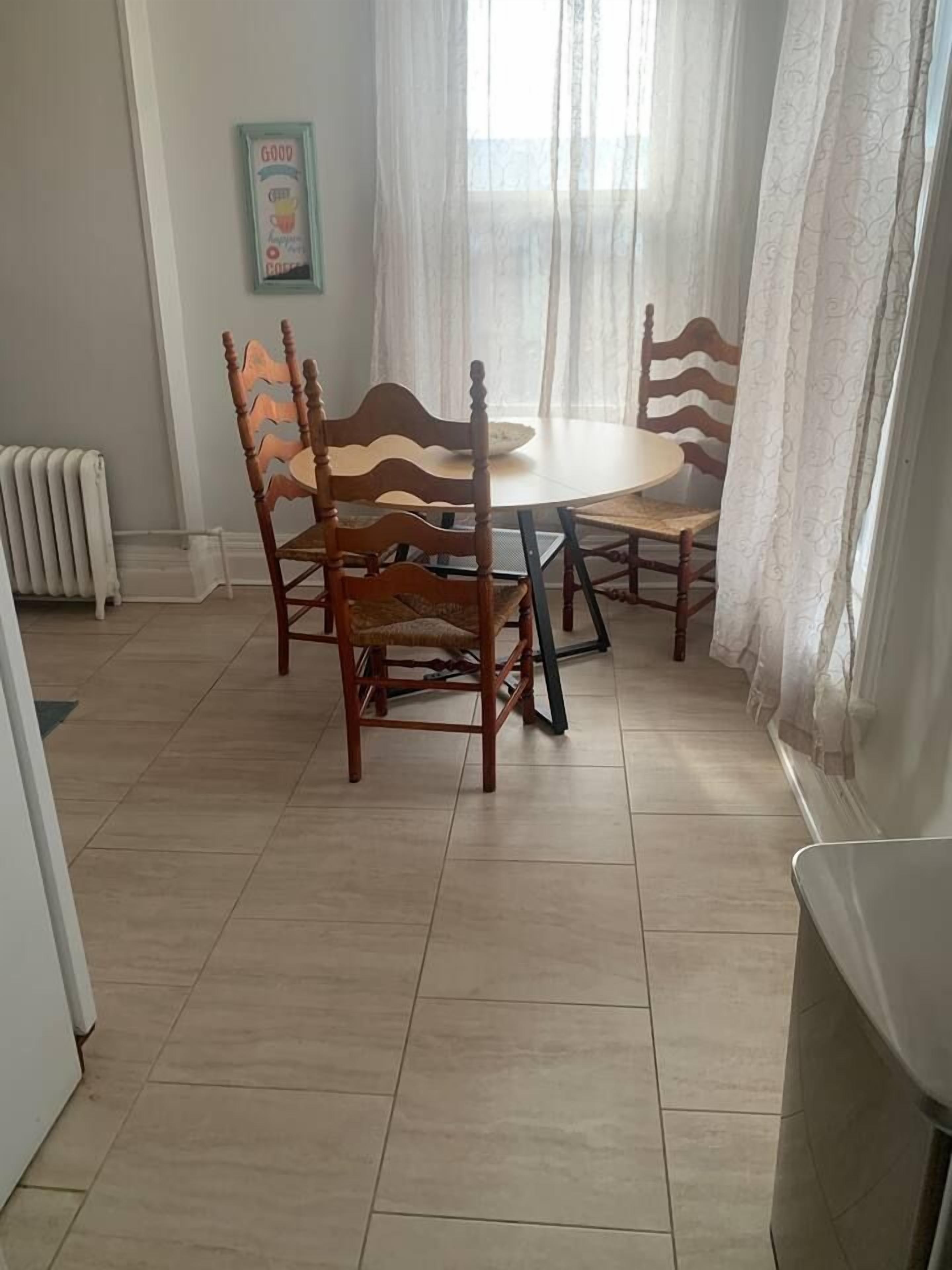 Un comedor con una mesa redonda y cuatro sillas de madera.