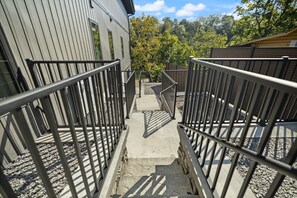 A concrete staircase with metal railings leading to a building with vertical siding. - The Gwinn | Luxury 6BR Lake Retreat, Hot Tub (Boyle County)