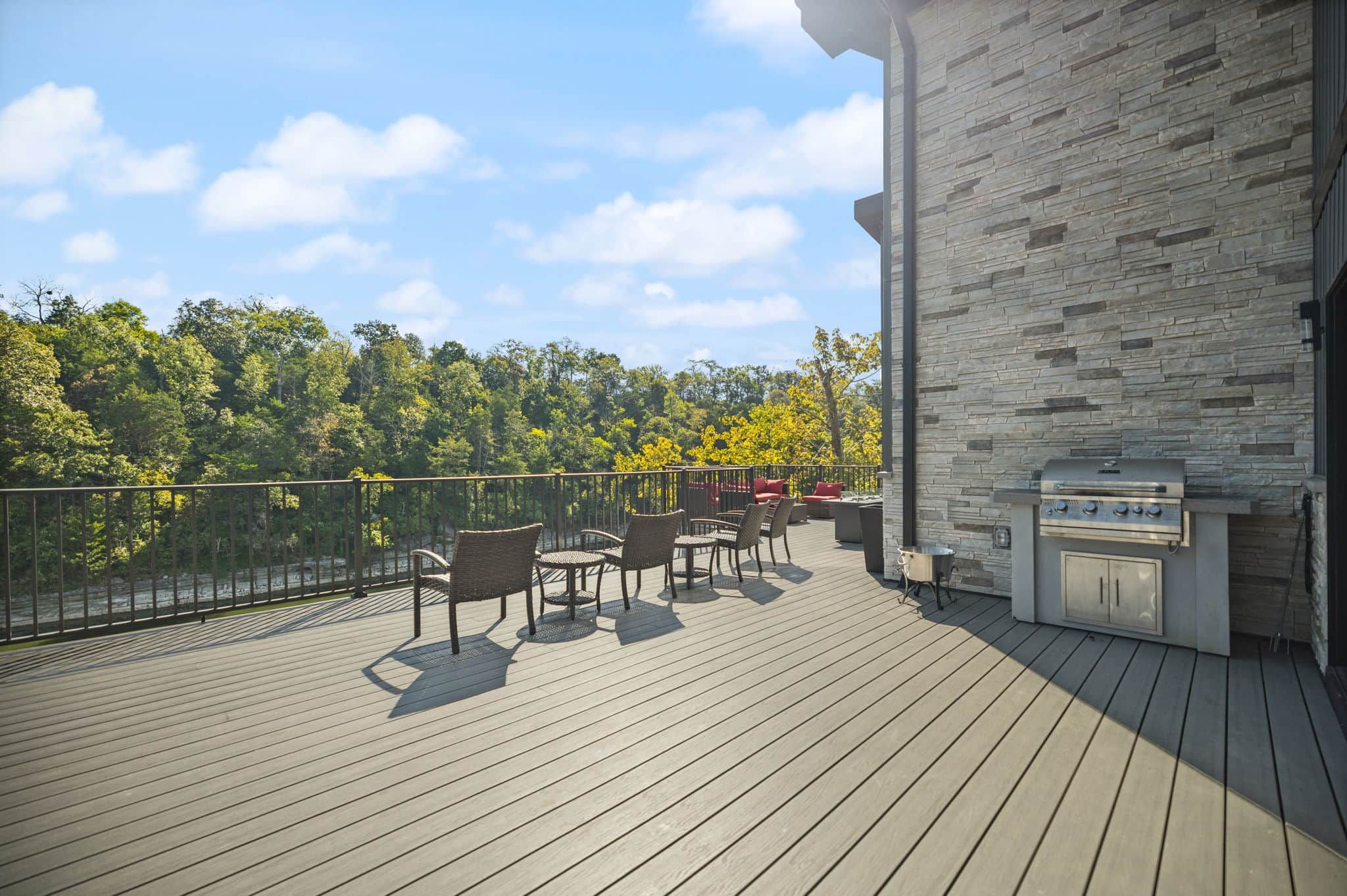 An outdoor deck with a stone wall and a barbecue grill.