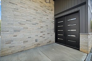 Un garage avec un mur en pierre et une porte de garage noire.
