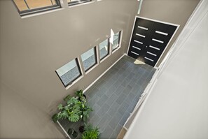 A modern interior with a tiled floor, a black door with multiple handles, and a row of framed pictures on the wall. - The Gwinn | Luxury 6BR Lake Retreat, Hot Tub (Boyle County)