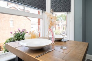 A dining table with a white plate, a glass, and a vase with dried flowers.