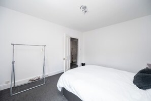 Quarto com cama, guarda-roupa e porta para outro espaço.