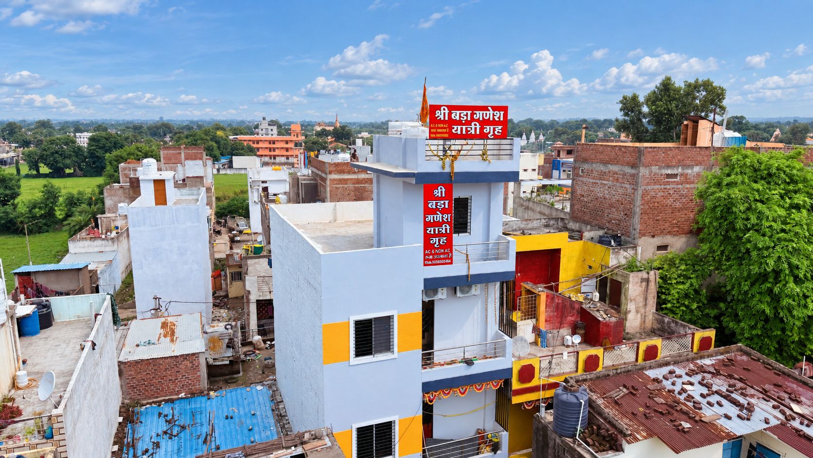A multi-story building with a prominent red sign, surrounded by other buildings and greenery.