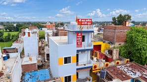 A multi-story building with a prominent red sign, surrounded by other buildings and greenery.