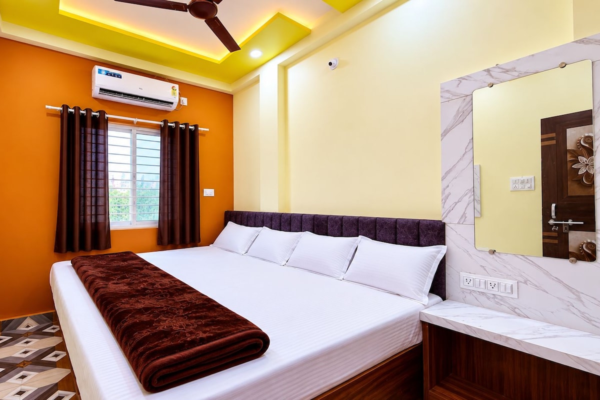 A hotel room with a bed, a television, an air conditioning unit, and a ceiling fan.