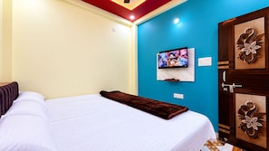 Una habitación de hotel con cama, televisor montado en la pared y puerta con paneles decorativos.