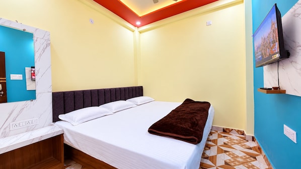 Una habitación de hotel con cama, televisor montado en la pared y baño con espejo y lavabo.