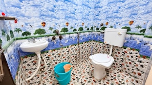 A bathroom with a mural of a tropical landscape, a sink, a toilet, and a bucket. - Shree Bada Ganesh Yatri Grah (Ujjain)