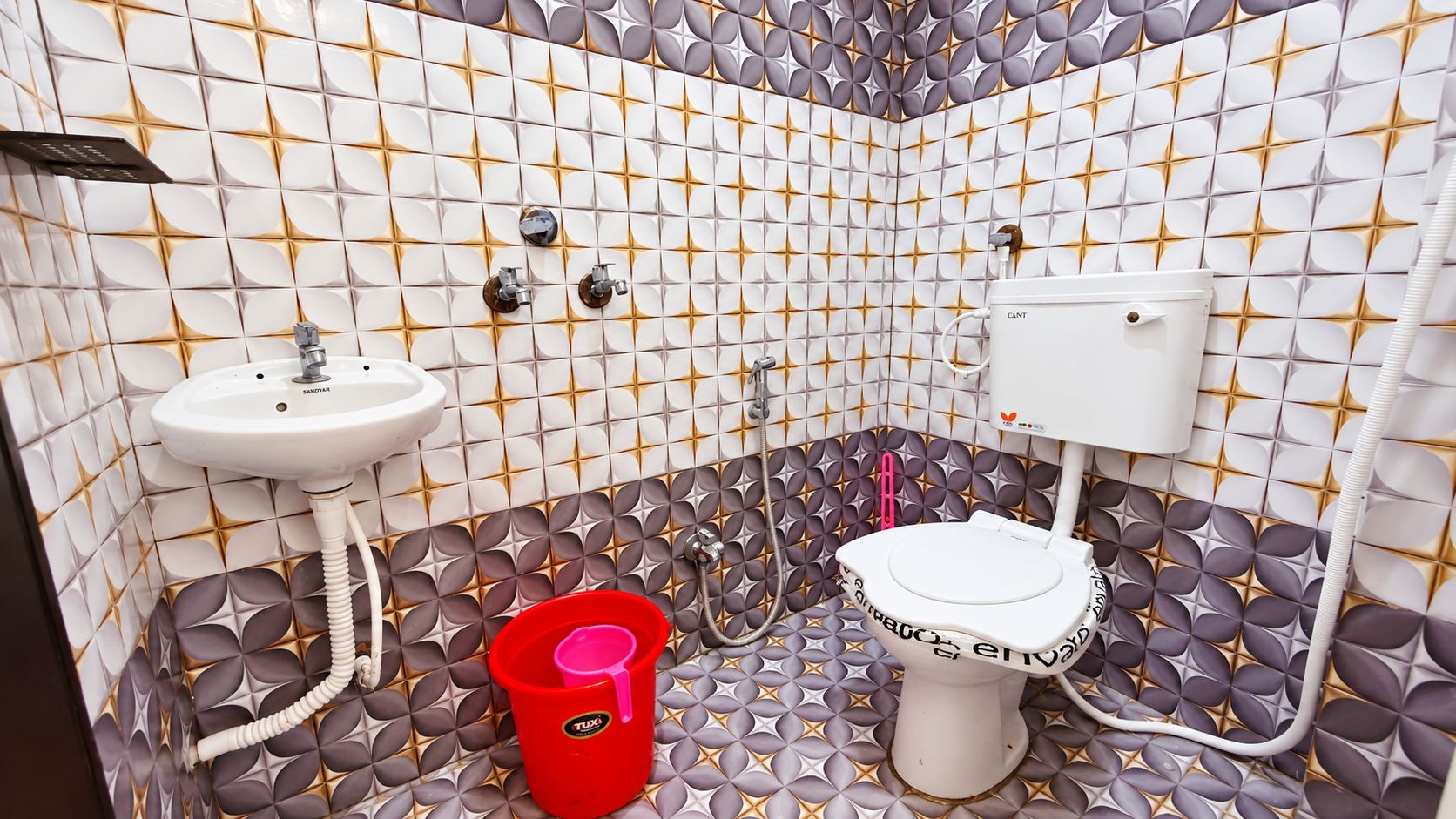 A bathroom with a white sink, a toilet, and a red bucket.