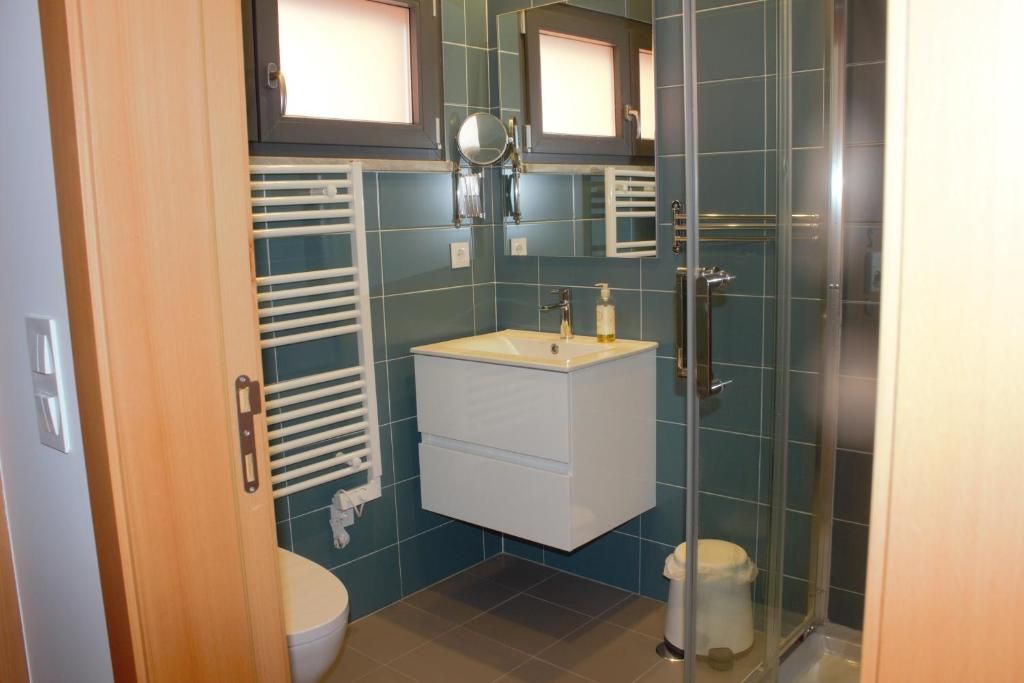 A bathroom with a glass shower enclosure, a white sink, and a towel rack.
