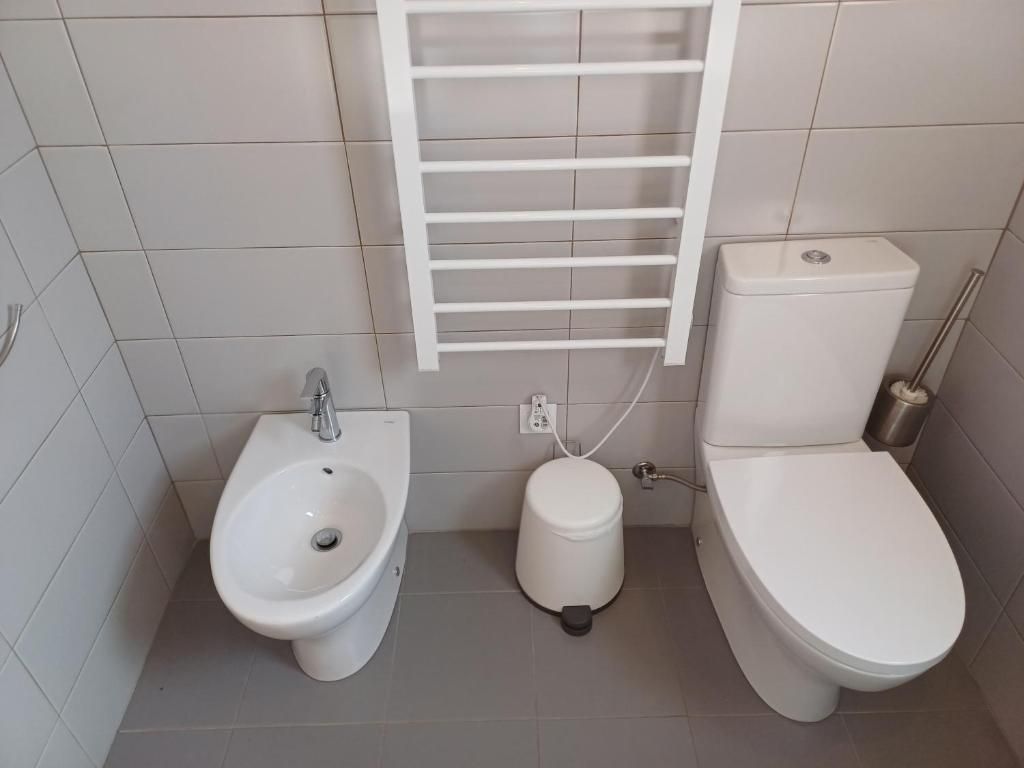 Une salle de bain équipée d’un bidet, de toilettes et d’un porte-serviettes.