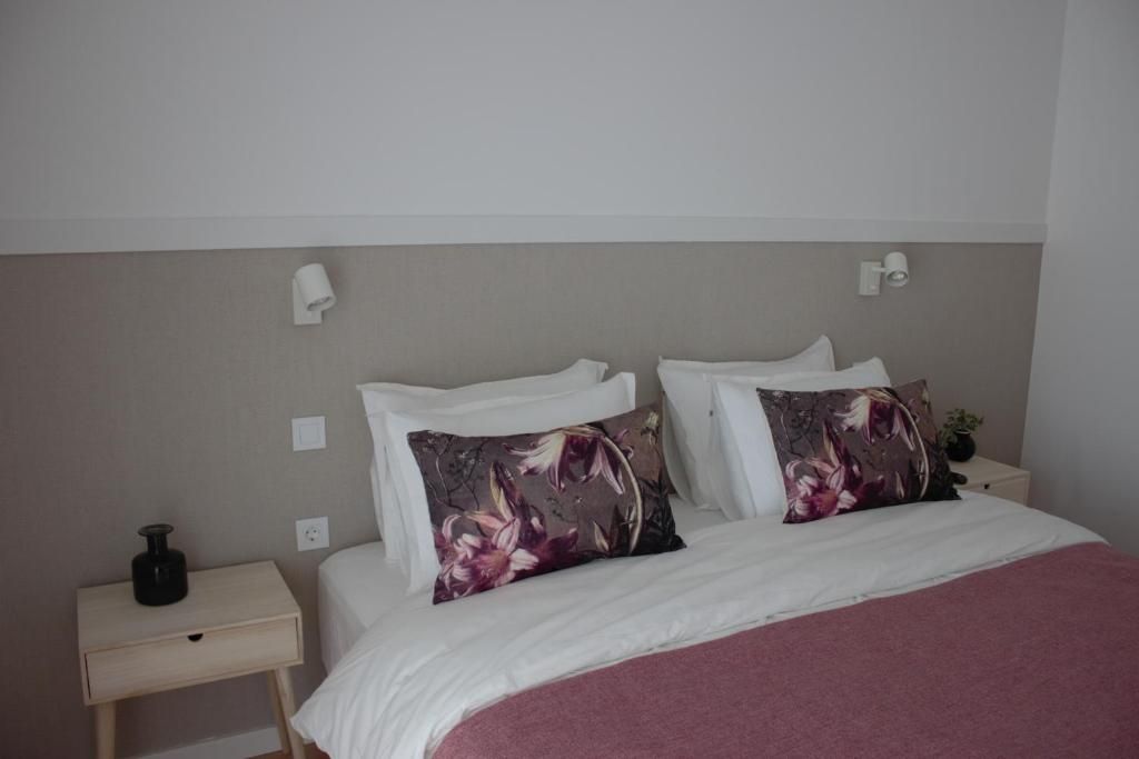 Une chambre à coucher avec un lit, deux oreillers, une table de chevet, une lampe et une petite table sur laquelle se trouve une bouteille.