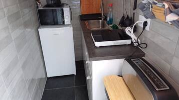 Una kitchenette compacta con microondas, tostadora y cafetera.