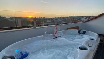 Ett bubbelbad på ett tak med utsikt över staden i solnedgången.