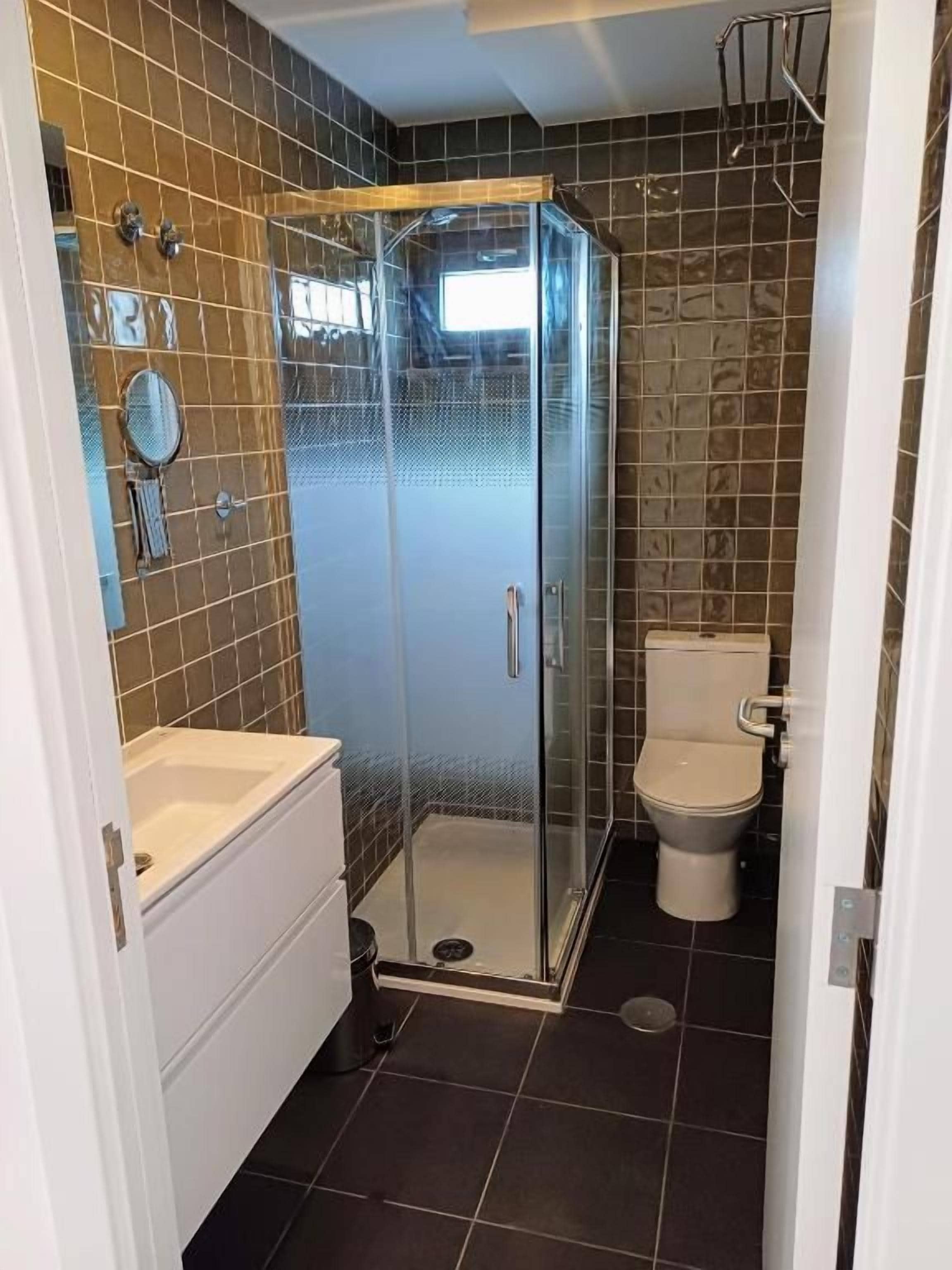 A bathroom with a glass-enclosed shower, a toilet, and a sink.