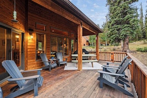 A wooden cabin with a covered deck, outdoor seating, and a view of the surrounding forest. - Keystone Ranch Escape | Hot Tub + Grill + Deck (Dillon)