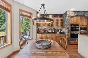 Eine moderne Küche mit einer Wand aus Stein, Holzschränken und einem Essbereich mit großem Tisch und Stühlen.