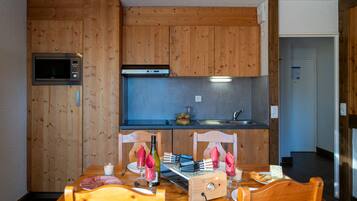 A compact kitchen with wooden cabinets, a microwave, and a built-in oven.