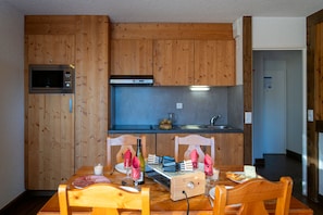 A compact kitchen with wooden cabinets, a microwave, and a built-in oven.