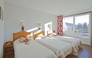 A hotel room with two beds, a wooden headboard, a window with a view of the outdoors, and a small wooden nightstand.