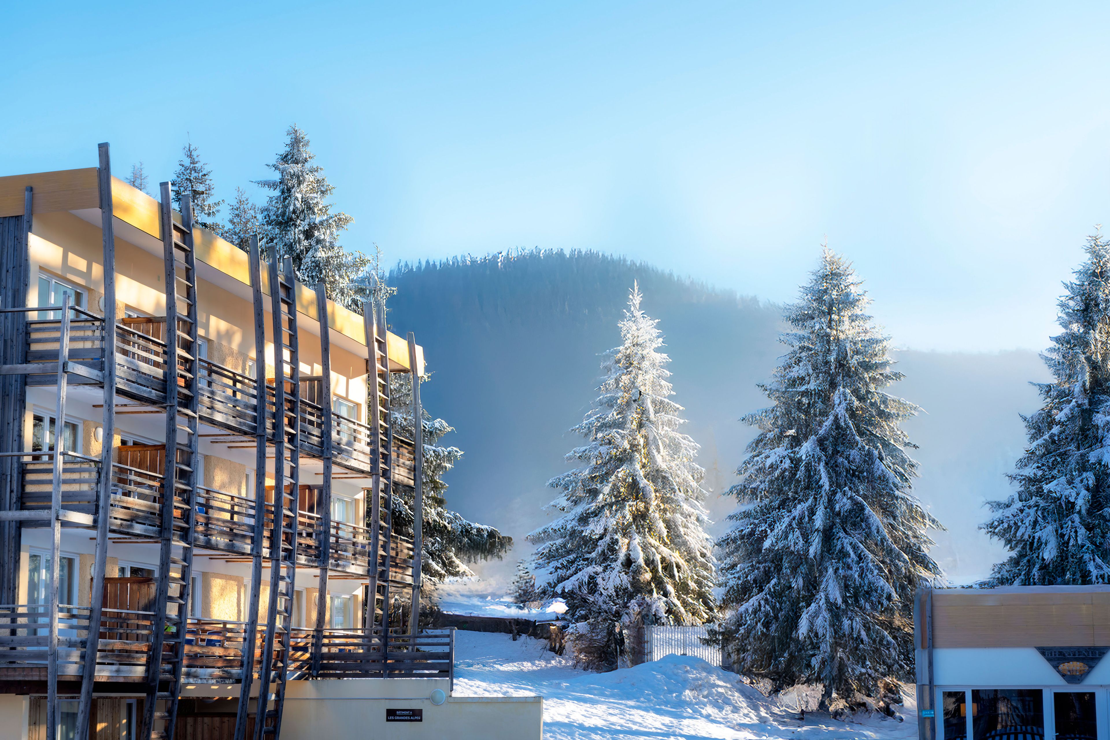 A building with a wooden staircase and a snow-covered mountain in the background.
