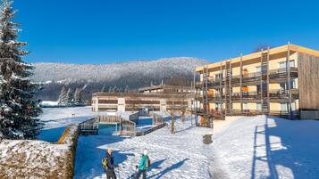 A snow-covered landscape with a building featuring multiple balconies and a ski lift.