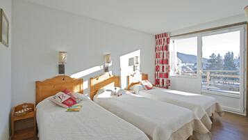 A hotel room with two beds, a wooden headboard, a window with a view of the outdoors, and a small wooden nightstand.