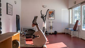 A gym with exercise equipment, a poster on the wall, and a window with a view of trees.