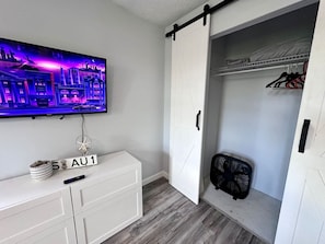 A room with a sliding closet door, a television mounted on the wall, a small fan, and a sign with 'AU1' on the dresser. - Quiet & near downtown Carnegie (Carnegie)