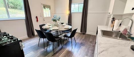 A dining area with a table set for four, a kitchen with a sink and cabinets, and a fire extinguisher on the wall.