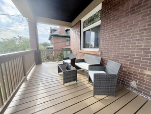 Eine überdachte Terrasse mit Korbmöbeln und einer Ziegelwand.