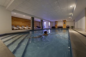 Indoor swimming pool with a swimmer and lounge chairs alongside - Au cœur de Vaujany | Piscine | Télécabine à 600 m (Vaujany)