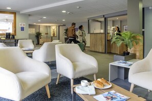 A hotel lobby with seating areas, a reception desk, and a coffee table with pastries. - Vue sur les montagnes | Piscine | Télécabine 600 m (Vaujany)
