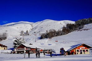 A ski resort with a wooden lodge, ski lifts, and a snow-covered mountain in the background. - Piscine chauffée | Sauna gratuit | Vue montagne (Saint-Jean-d'Arves)