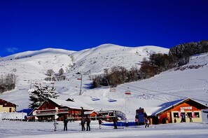 Une station de ski avec un chalet en bois, des remontées mécaniques et une montagne enneigée en arrière-plan.