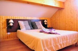 Ein Schlafzimmer mit einem hölzernen Kopfende, zwei Nachttischlampen, einem Bett mit einem gestreiften Kissen und einer Decke.