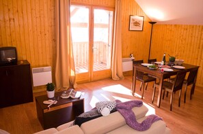Ein gemütliches Wohnzimmer mit einer Couch, einem Couchtisch, einem Fernseher und einer Essecke mit Tisch und Stühlen.
