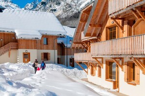 A wooden chalet with a snow-covered roof and a wooden staircase leading to the entrance.
